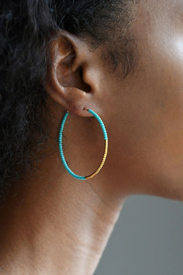 Close-up of a person wearing a sidai turquoise beaded hoop earring for ichyulu